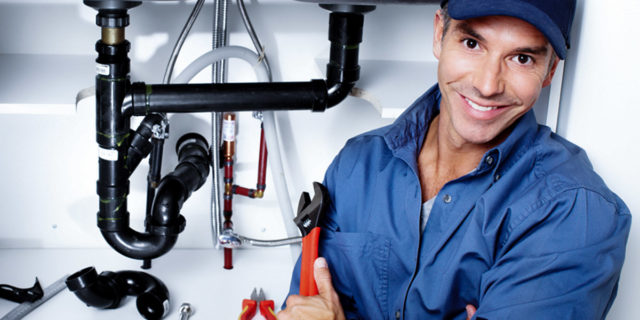 Technician in front of kitchen sink pipes.