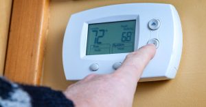 Person turning up the heat on thermostat